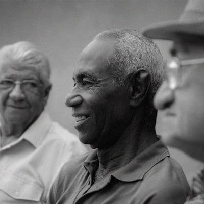 Three men smiling and congratulating each other while playing a game of soccer in the park