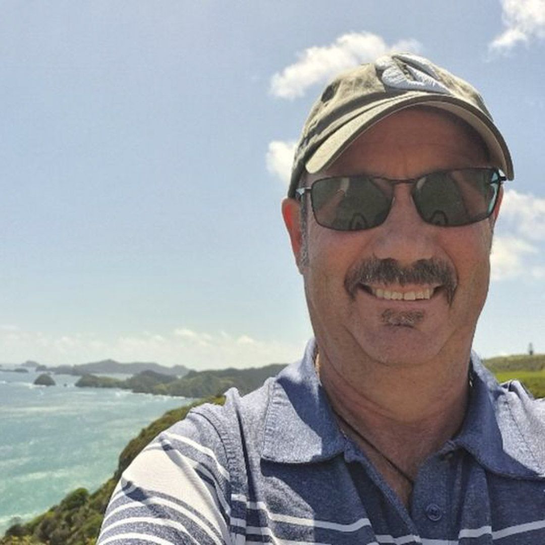 Photo of a man with a moustache, smiling to camera.