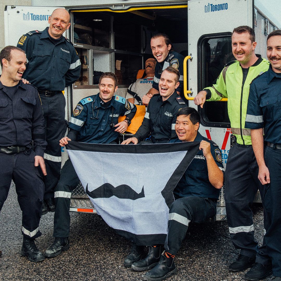 Photo showing first responders holding a Movember-branded flag.