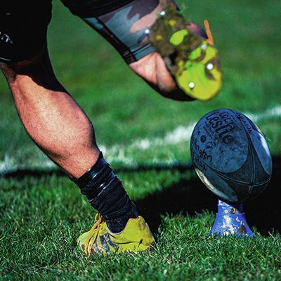 Close-up photo of a rugby player about to kick a football.